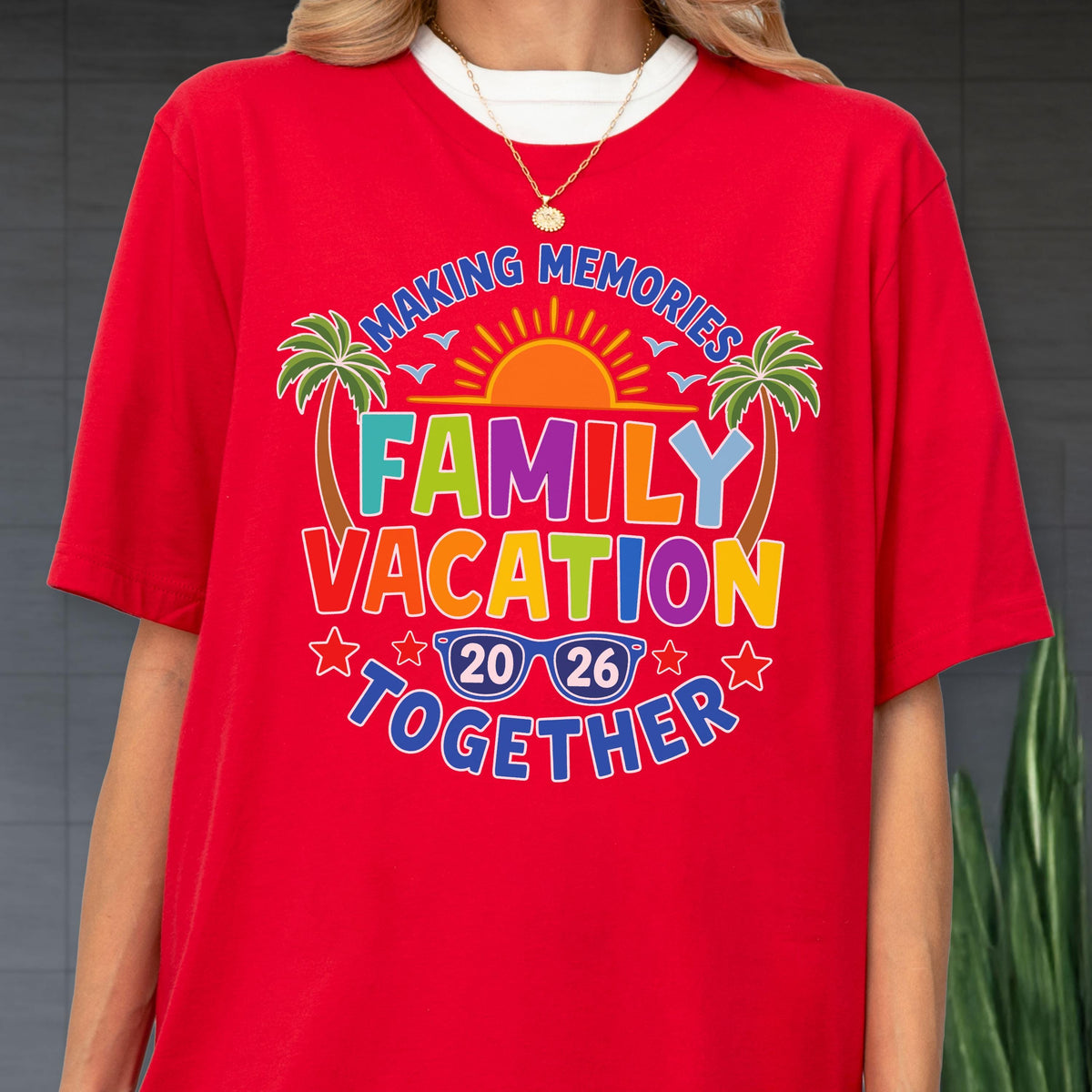 May include: A bright red t-shirt featuring a colorful graphic with the text "MAKING MEMORIES FAMILY VACATION TOGETHER" and "20 26" inside blue sunglasses. The design includes a yellow sun, two green palm trees, and small red stars.