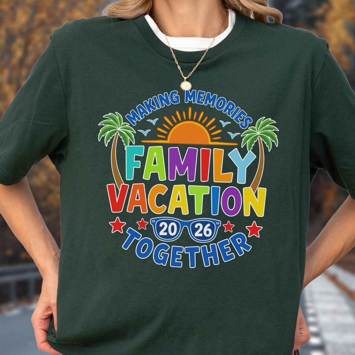 May include: A dark green short-sleeve t-shirt featuring a colorful graphic with the text "MAKING MEMORIES FAMILY VACATION TOGETHER 20 26". The design includes a sun, two palm trees, and blue sunglasses, all rendered in vibrant shades of red, orange, yellow, green, and blue.