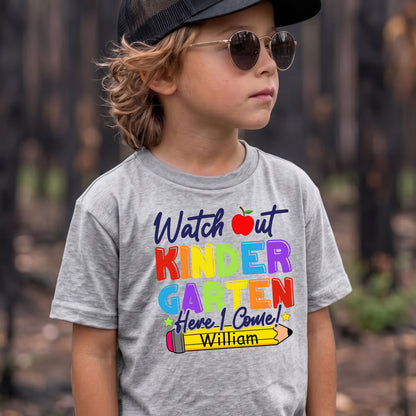 May include: A heather gray t-shirt featuring the text Watch out KINDERGARTEN Here I Come! in colorful block letters, a red apple icon, and a yellow pencil graphic with the name William printed in black on the pencil body.