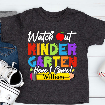 May include: A dark charcoal gray short-sleeve t-shirt featuring the text "Watch out KINDERGARTEN Here I Come!" in colorful block letters. A red apple icon replaces the "o" in "out" and a yellow pencil graphic displays the name "William".