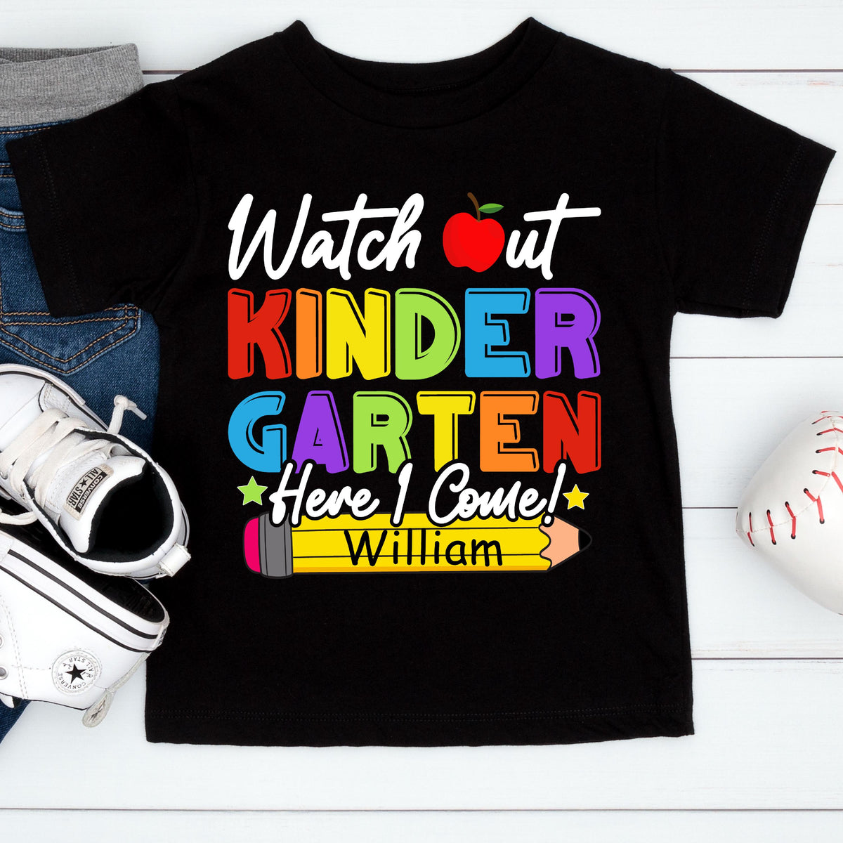 May include: A black short-sleeve t-shirt featuring the text "Watch out KINDERGARTEN Here I Come!" in colorful letters, a red apple graphic, a yellow pencil graphic with the name "William" printed on it, and two small stars.