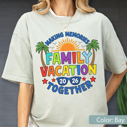 May include: A light gray short-sleeve t-shirt featuring a colorful graphic with the text MAKING MEMORIES FAMILY VACATION TOGETHER 20 26. The design includes a bright orange sun, two palm trees, small birds, and blue sunglasses with the year.