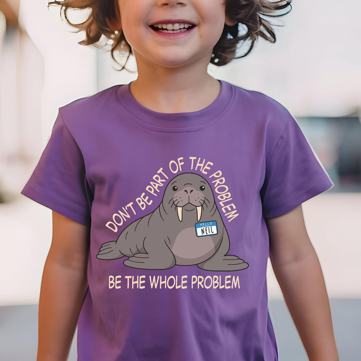 May include: A purple short-sleeved t-shirt featuring a cartoon walrus with a name tag that reads NEIL. The text above the walrus reads DON'T BE PART OF THE PROBLEM and the text below reads BE THE WHOLE PROBLEM in light-colored capital letters.