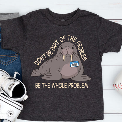 May include: A charcoal gray short-sleeve t-shirt featuring a cartoon walrus with a name tag that reads "HELLO NEIL". The text above the walrus says "DON'T BE PART OF THE PROBLEM" and the text below the walrus says "BE THE WHOLE PROBLEM".