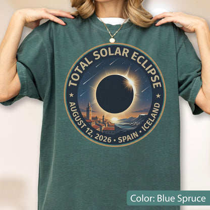 May include: A blue spruce crew neck t-shirt featuring a circular graphic of a total solar eclipse over a coastal town. The text reads TOTAL SOLAR ECLIPSE AUGUST 12, 2026 SPAIN ICELAND. The design includes a dark sun, rays, and stars.