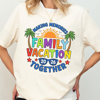 May include: A cream-colored t-shirt featuring a colorful graphic with the text "MAKING MEMORIES FAMILY VACATION TOGETHER 20 26". The design includes a bright orange sun, two green palm trees, blue sunglasses, and red stars, all arranged in a vibrant, multi-colored layout.