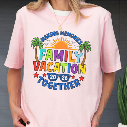 May include: A light pink t-shirt featuring a colorful graphic with the text "MAKING MEMORIES FAMILY VACATION TOGETHER 20 26". The design includes a bright orange sun, two green palm trees, blue sunglasses, and small red stars on a light pink background.