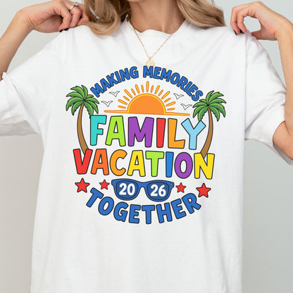 May include: A white t-shirt featuring a colorful graphic with the text "MAKING MEMORIES FAMILY VACATION TOGETHER 20 26". The design includes a bright orange sun, green palm trees, blue sunglasses, and red stars, creating a vibrant summer-themed print.