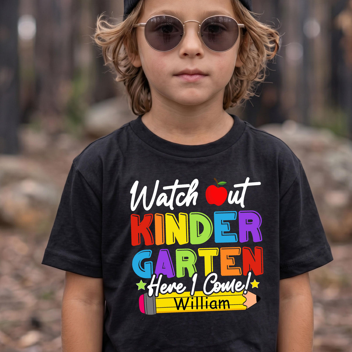 May include: A black t-shirt featuring the text "Watch out KINDERGARTEN Here I Come!" in colorful block letters, a red apple icon, and a yellow pencil graphic at the bottom with the name "William" printed in black on the pencil body.