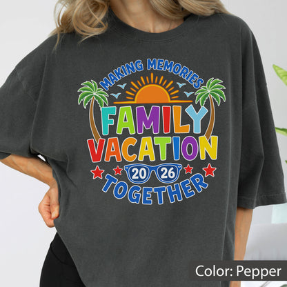 May include: A charcoal gray t-shirt featuring a colorful graphic with the text "MAKING MEMORIES FAMILY VACATION TOGETHER 2026". The design includes a bright orange sun, two green palm trees, blue sunglasses, and red stars, all printed on the front of the shirt.