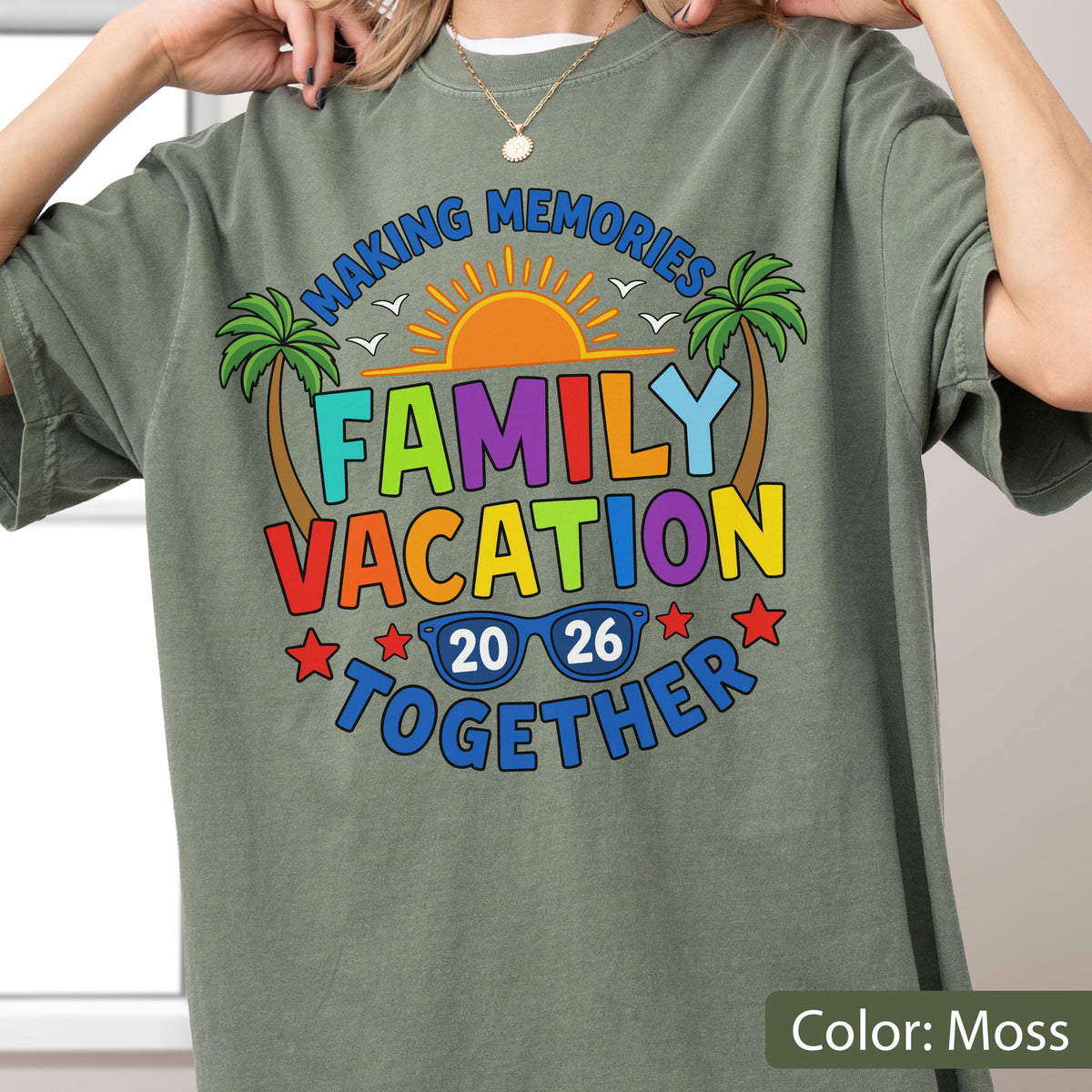 May include: A moss green t-shirt featuring a graphic with the text "MAKING MEMORIES FAMILY VACATION TOGETHER 20 26". The design includes a bright orange sun, two green palm trees, blue sunglasses, and red stars, creating a vibrant summer theme.