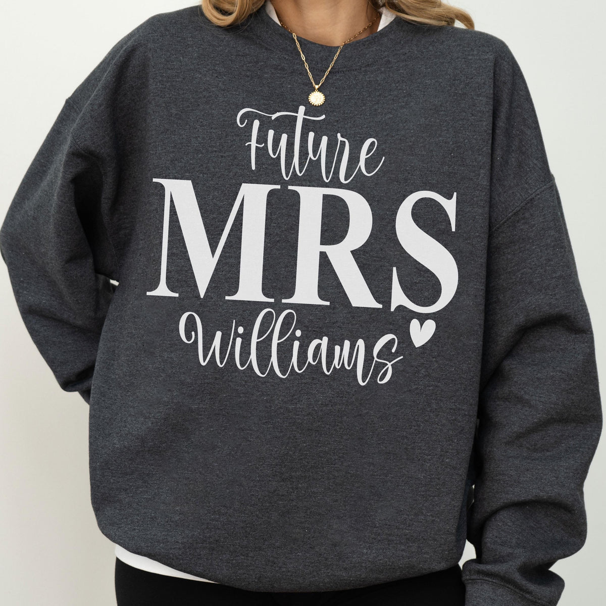 May include: A dark charcoal gray crewneck sweatshirt featuring the white text "Future MRS Williams" printed on the front. The word "Future" and "Williams" are in a cursive script font, while "MRS" is in a large, bold, sans-serif font.