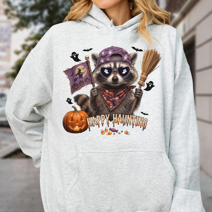 May include: A light gray hooded sweatshirt featuring a graphic of a raccoon wearing a purple baseball cap, heart-shaped sunglasses with ghost reflections, and a patterned bandana. The raccoon holds a broom and a flag. Text reads HAPPY HAUNTING.