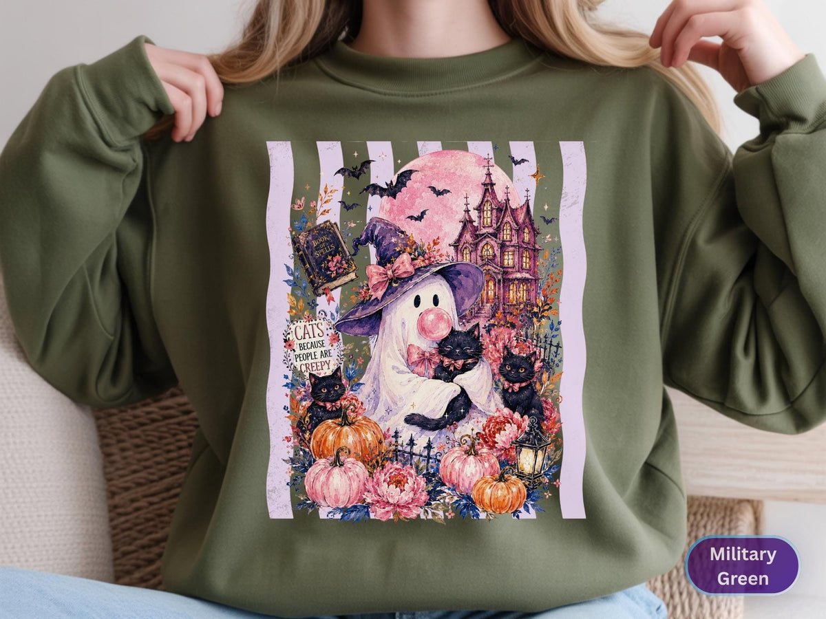 May include: A military green crewneck sweatshirt featuring a graphic print of a ghost wearing a witch hat, holding black cats, with pumpkins, a haunted house, and a full moon. The text reads, "CATS BECAUSE PEOPLE ARE CREEPY" on a white striped background.