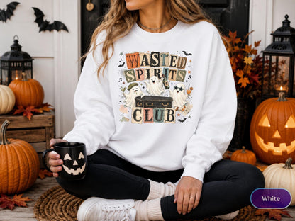 May include: A white long-sleeve sweatshirt featuring a graphic print with the text Wasted Spirits Club in block letters. The design includes three cartoon ghosts around a coffin, with one ghost wearing a beret and another wearing star-shaped glasses.