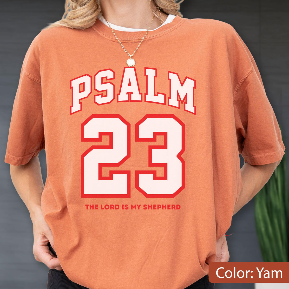 May include: A yam-colored short-sleeve t-shirt featuring the white text PSALM 23 in a collegiate font, with the number 23 in large white digits outlined in red, and the text THE LORD IS MY SHEPHERD printed in small red capital letters below.