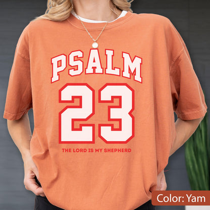 May include: A yam-colored short-sleeve t-shirt featuring the white text PSALM 23 in a collegiate font, with the number 23 in large white digits outlined in red, and the text THE LORD IS MY SHEPHERD printed in small red capital letters below.