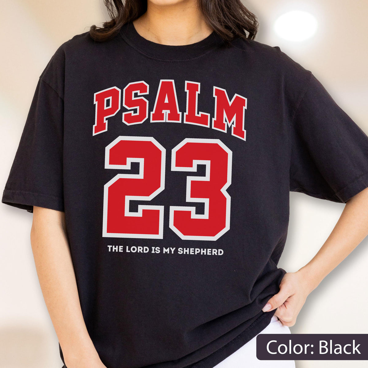 May include: A black short-sleeve t-shirt featuring the red text PSALM 23 in a collegiate font, with the number 23 in large red digits outlined in white, and the white text THE LORD IS MY SHEPHERD printed underneath the number.
