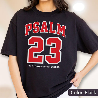 May include: A black short-sleeve t-shirt featuring the red text PSALM 23 in a collegiate font, with the number 23 in large red digits outlined in white, and the white text THE LORD IS MY SHEPHERD printed underneath the number.