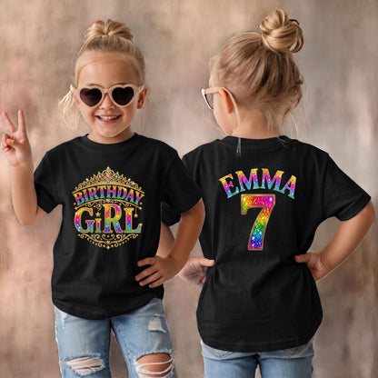 May include: A black t-shirt featuring a gold crown graphic with the text Birthday Girl in rainbow colors on the front, and the name Emma with the number 7 in rainbow colors on the back, paired with light blue distressed denim jeans.