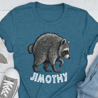 May include: A teal blue t-shirt featuring a detailed graphic of a raccoon with intricate leaf-like patterns in its fur. Below the raccoon, the name JIMOTHY is printed in bold, white, capital letters. The shirt has a crew neckline and short sleeves.