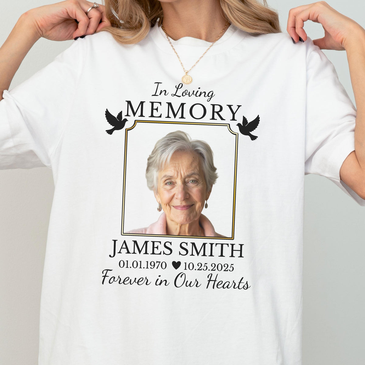May include: A white t-shirt featuring a memorial design with the text In Loving Memory, a framed photograph of an older person, the name James Smith, the dates 01.01.1970 and 10.25.2025, a heart icon, and the phrase Forever in Our Hearts with two black birds.
