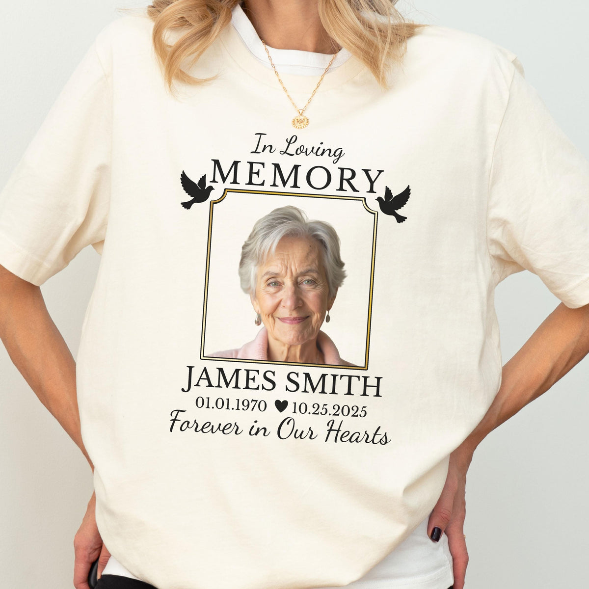 May include: A cream-colored t-shirt featuring a memorial graphic with the text In Loving Memory, the name James Smith, dates 01.01.1970 and 10.25.2025, the phrase Forever in Our Hearts, a photograph of an older person, and two black flying birds.