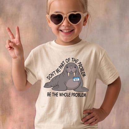 May include: A cream-colored t-shirt featuring a graphic of a grey walrus wearing a blue name tag that says NEIL. The text above and below the walrus reads DON'T BE PART OF THE PROBLEM BE THE WHOLE PROBLEM in black capital letters.