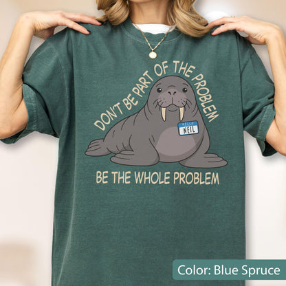 May include: A blue spruce t-shirt featuring a graphic of a grey walrus with tusks wearing a name tag that reads HELLO NEIL. The text above the walrus reads DON'T BE PART OF THE PROBLEM and the text below reads BE THE WHOLE PROBLEM in light tan.