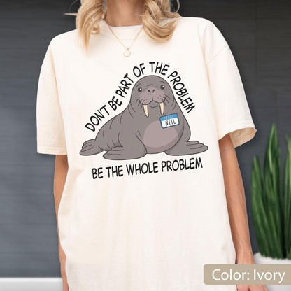 May include: An ivory t-shirt featuring a graphic of a grey walrus wearing a blue name tag that reads "HELLO NEIL". The text above the walrus reads "DON'T BE PART OF THE PROBLEM" and the text below the walrus reads "BE THE WHOLE PROBLEM".
