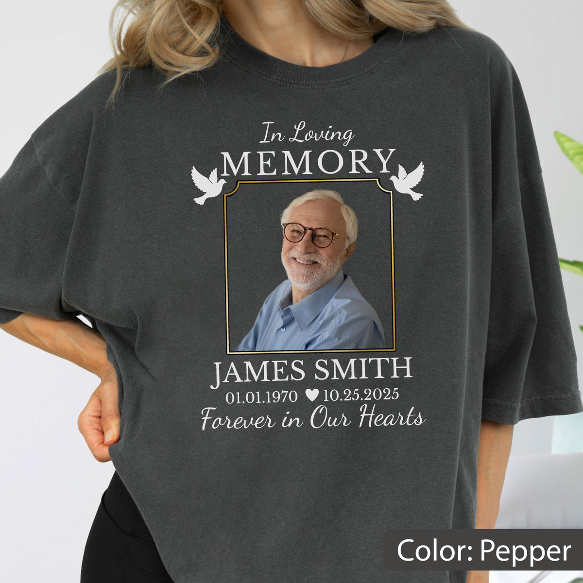 May include: A charcoal gray t-shirt featuring a memorial graphic with the text In Loving Memory, the name James Smith, dates 01.01.1970 to 10.25.2025, and the phrase Forever in Our Hearts, centered around a photograph of a man wearing glasses.