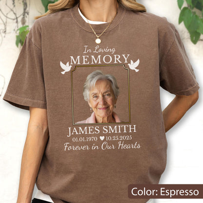 May include: An espresso-colored t-shirt featuring a memorial graphic with the text In Loving Memory, a framed photograph of an older person, the name James Smith, the dates 01.01.1970 to 10.25.2025, a heart icon, and the phrase Forever in Our Hearts.