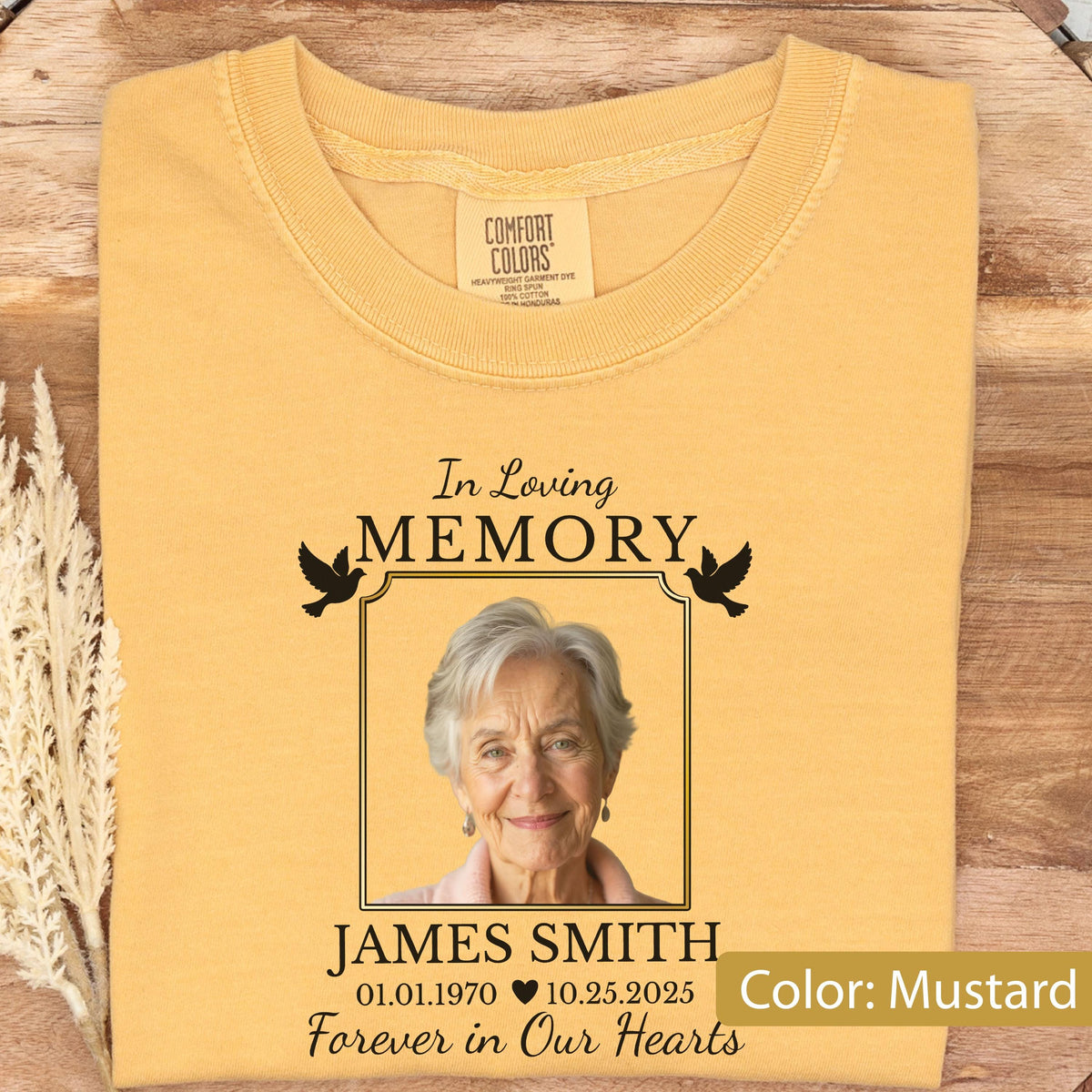 May include: A mustard yellow t-shirt featuring a memorial graphic with the text In Loving Memory, the name James Smith, the dates 01.01.1970 and 10.25.2025, a heart symbol, the phrase Forever in Our Hearts, and a photograph of an older person.