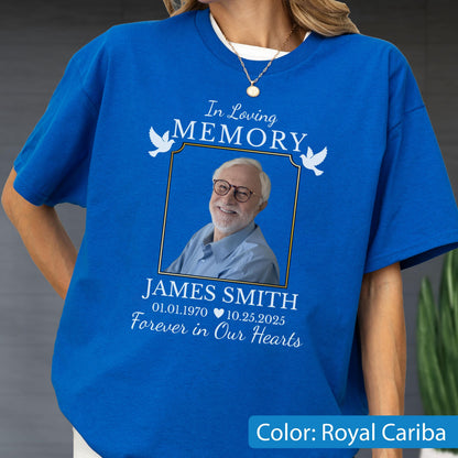 May include: A royal blue t-shirt featuring a memorial graphic with the text In Loving Memory, James Smith, 01.01.1970, 10.25.2025, and Forever in Our Hearts. The design includes a framed photograph of an older person with glasses and white doves.