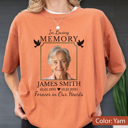 May include: A burnt orange short-sleeve t-shirt featuring a memorial graphic with the text In Loving Memory, James Smith, 01.01.1970 - 10.25.2025, and Forever in Our Hearts, surrounding a portrait of an older person with two black bird silhouettes.