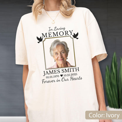 May include: An ivory t-shirt featuring a memorial graphic with the text In Loving MEMORY, a framed photograph of an older person, the name JAMES SMITH, the dates 01.01.1970 and 10.25.2025 separated by a heart, and the phrase Forever in Our Hearts.
