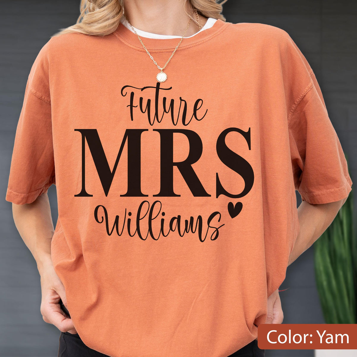 May include: A yam-colored short-sleeve t-shirt featuring the black printed text Future MRS Williams with a small heart icon. The shirt has a crew neckline and a relaxed fit, showcasing a bold script and serif font combination on the front chest area.