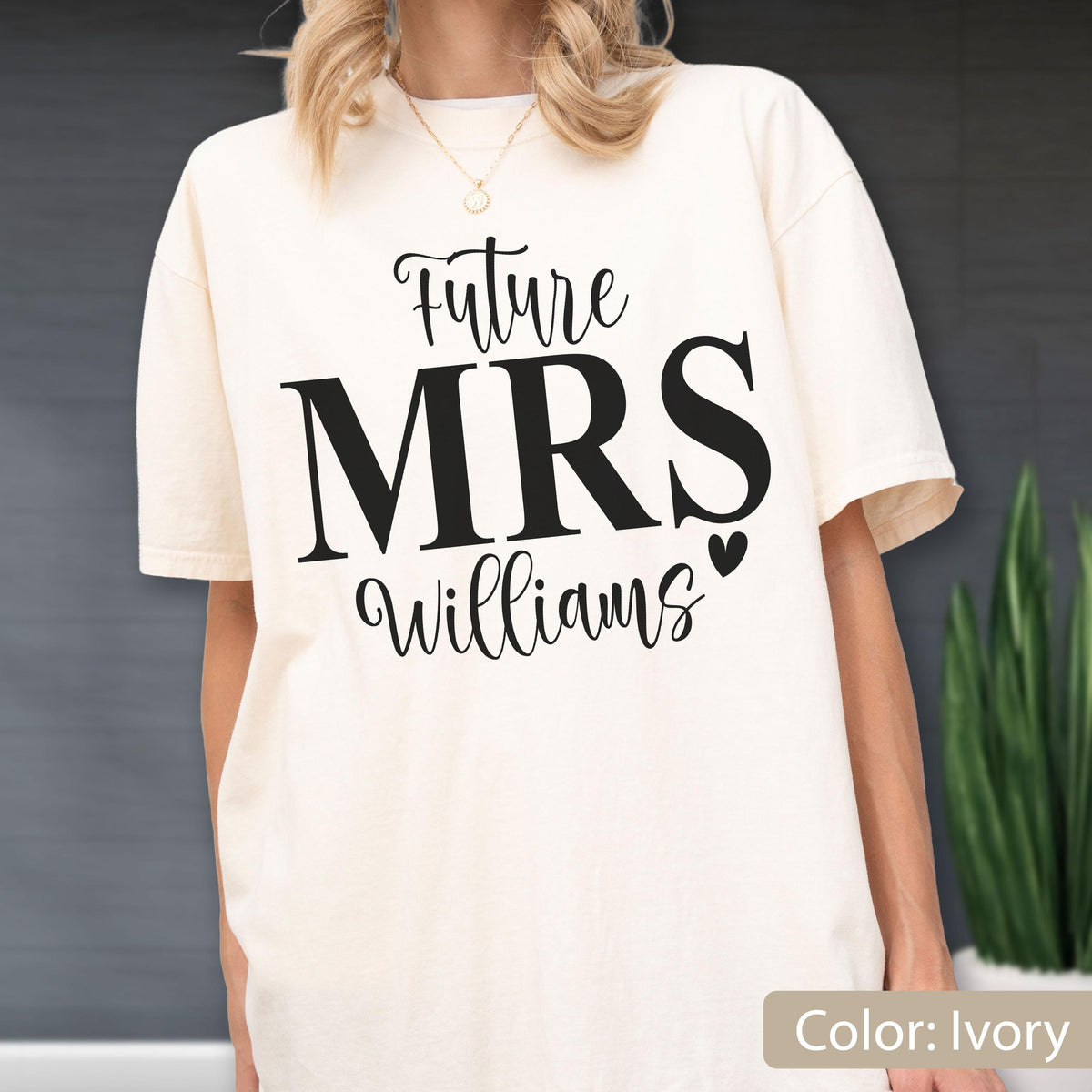 May include: An ivory short-sleeved t-shirt featuring black text that reads Future MRS Williams with a small heart icon. The shirt has a crew neckline and a relaxed fit, showcasing a bold graphic design printed on the front center of the garment.