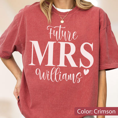 May include: A crimson short-sleeve t-shirt featuring white screen-printed text that reads Future MRS Williams with a small heart icon. The shirt has a crew neckline and a relaxed fit, showcasing a washed-out, vintage-inspired fabric texture.