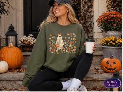 May include: A military green crewneck sweatshirt featuring a central graphic of a white ghost wearing an orange bow and holding a jack-o'-lantern bucket, surrounded by a colorful array of various flowers and small black bats.