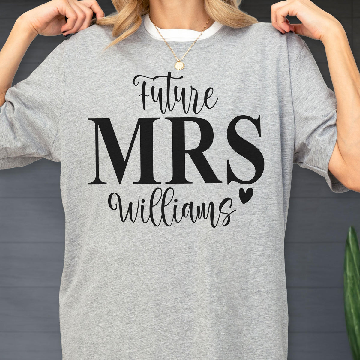 May include: A heather gray short-sleeve t-shirt featuring black text that reads Future MRS Williams with a small heart icon. The shirt has a crew neckline and is made of a soft fabric. The design is centered on the chest in a mix of script and serif fonts.