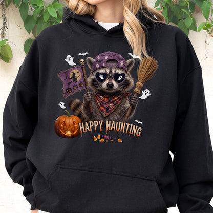 May include: A black hooded sweatshirt featuring a graphic of a raccoon wearing a purple baseball cap and heart-shaped sunglasses. The raccoon holds a broom and a flag with a witch silhouette. Text reads HAPPY HAUNTING with pumpkins and ghosts.