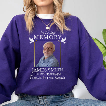May include: A purple crewneck sweatshirt featuring a memorial graphic with the text In Loving Memory, James Smith, 01.01.1970, 10.25.2025, and Forever in Our Hearts, surrounding a photograph of a smiling person with glasses and a light blue shirt.