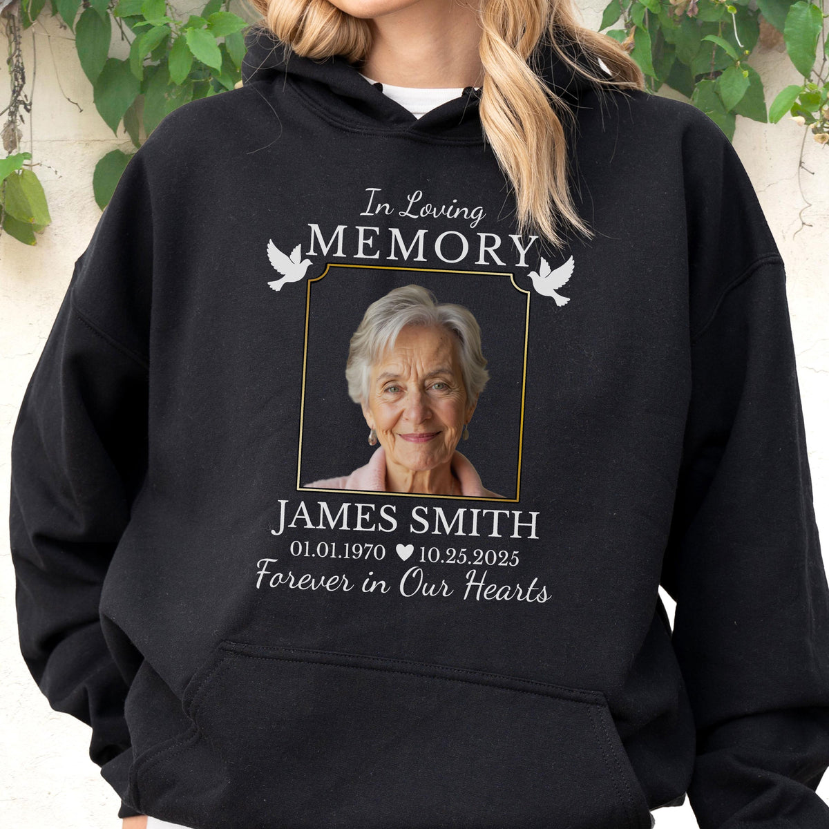 May include: A black hooded sweatshirt featuring a memorial graphic with the text In Loving Memory, a photograph of an older person, the name James Smith, the dates 01.01.1970 and 10.25.2025, a heart icon, and the phrase Forever in Our Hearts with two white doves.