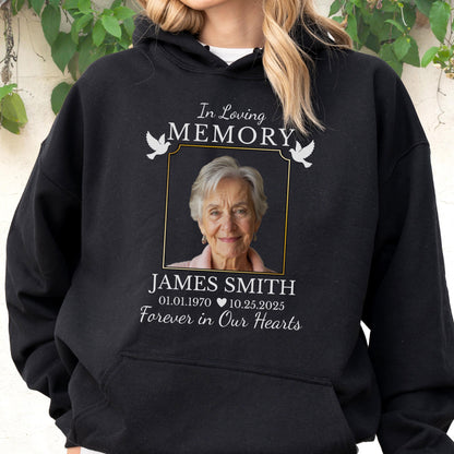 May include: A black hooded sweatshirt featuring a memorial graphic with the text In Loving Memory, a photograph of an older person, the name James Smith, the dates 01.01.1970 and 10.25.2025, a heart icon, and the phrase Forever in Our Hearts with two white doves.