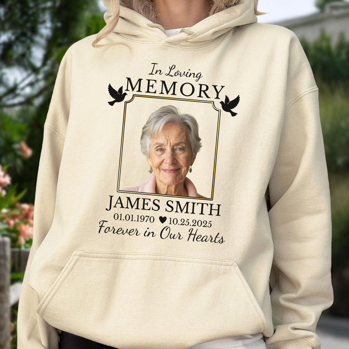 May include: A cream-colored hooded sweatshirt featuring a memorial graphic with the text In Loving Memory, the name James Smith, dates 01.01.1970 and 10.25.2025, the phrase Forever in Our Hearts, two black bird silhouettes, and a portrait of an older person.