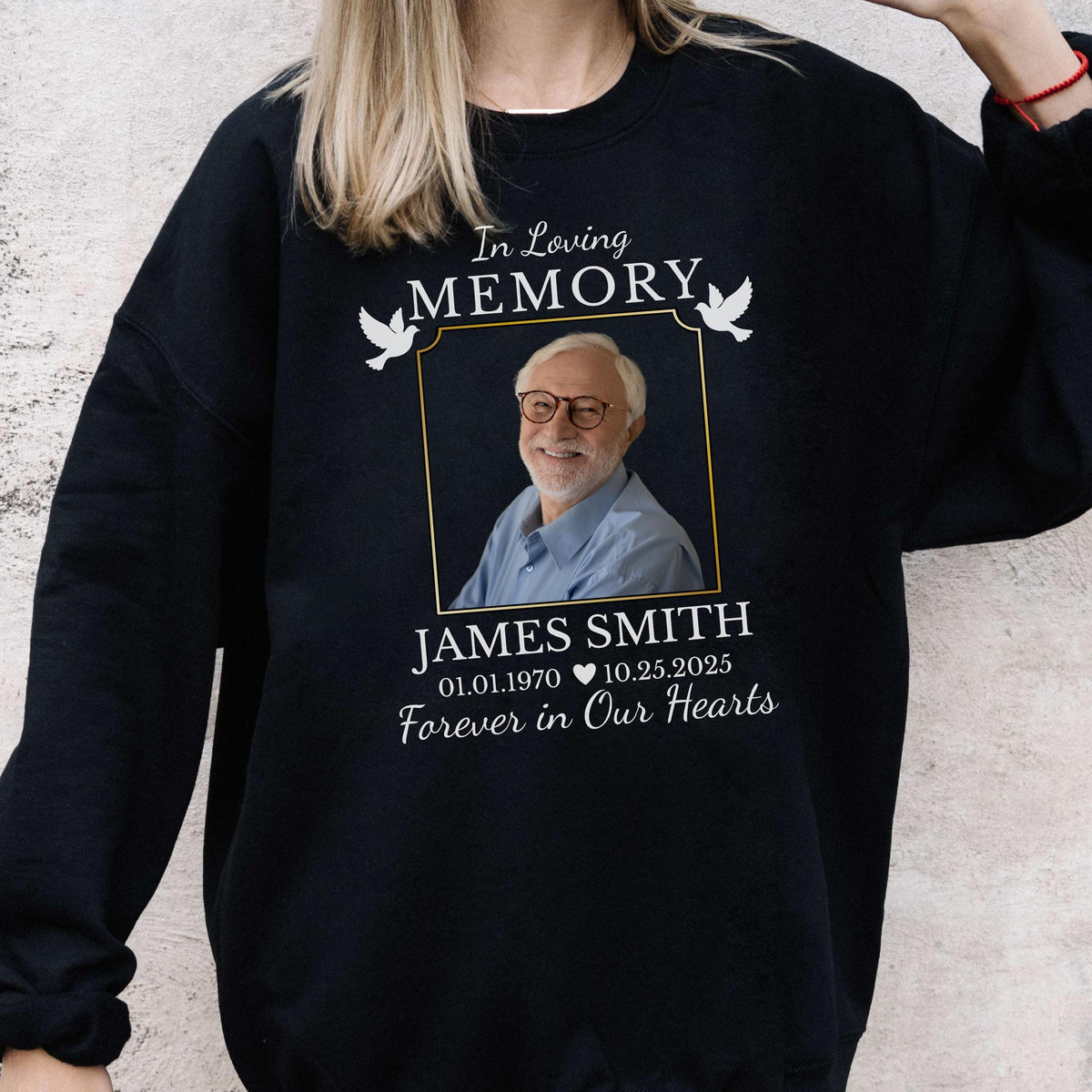 May include: A black crewneck sweatshirt featuring a memorial graphic with the text In Loving Memory, a framed photograph of a smiling person with glasses, the name James Smith, dates 01.01.1970 to 10.25.2025, and the phrase Forever in Our Hearts.