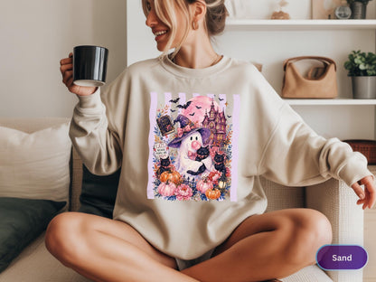 May include: A sand-colored crewneck sweatshirt featuring a graphic print of a ghost wearing a witch hat, holding a black cat, surrounded by pumpkins, flowers, a haunted house, and bats. The text on the graphic reads, "Cats, because people are creepy."