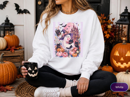 May include: A white long-sleeve sweatshirt featuring a graphic print of a ghost wearing a witch hat, holding black cats, surrounded by pumpkins, flowers, a haunted house, and bats. The text on the graphic reads Cats, Books, and Creepy.