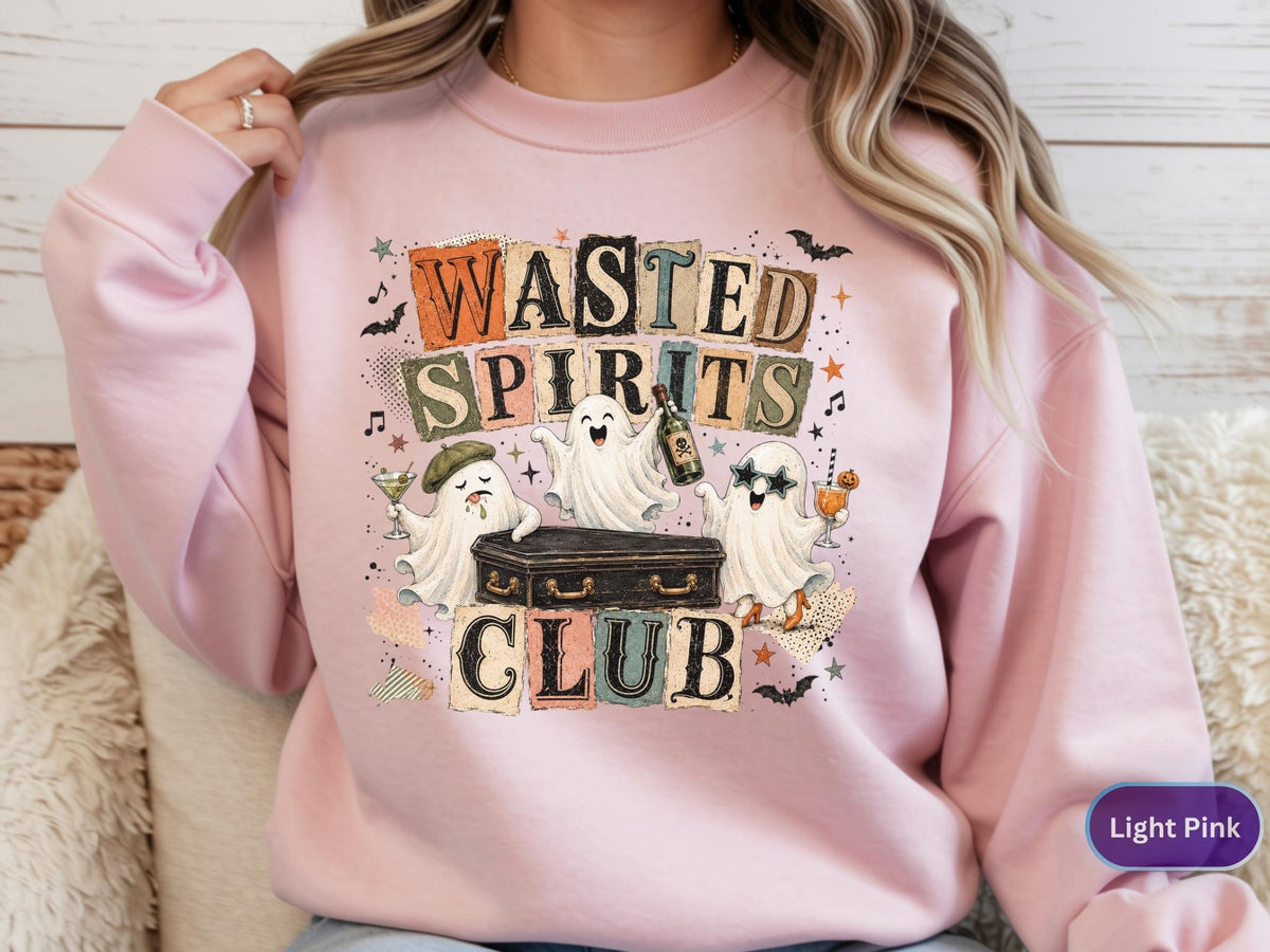 May include: A light pink crewneck sweatshirt featuring a graphic print with the text "WASTED SPIRITS CLUB" in block letters. The design includes three white ghosts, a black coffin, a green martini glass, a bottle, and small bats.